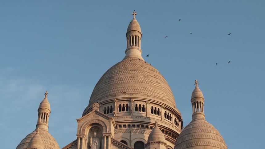 Birds flying around the the steeple of a cathedral Montmartre Paris
