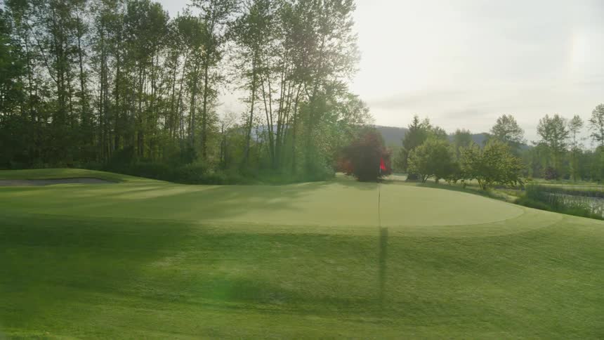 A red flag on a pole marks the hole on a golf course near the water hazard