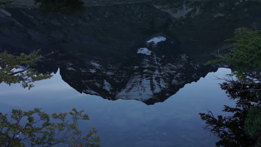 A mountain covered in snow is reflected in the water