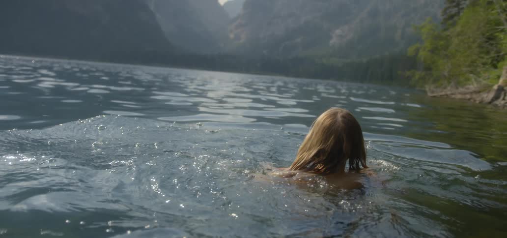 Woman swims in a lake near the mountains