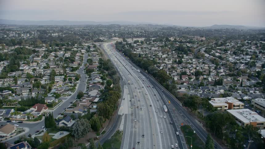 A wide highway with traffic surrounded by houses and neighborhoods