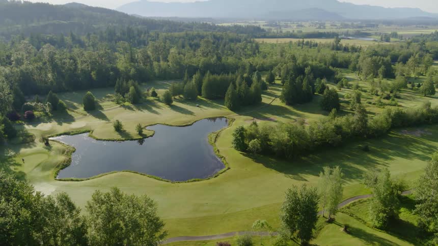 Pond occupies part of golf course surrounded by forest and mountains