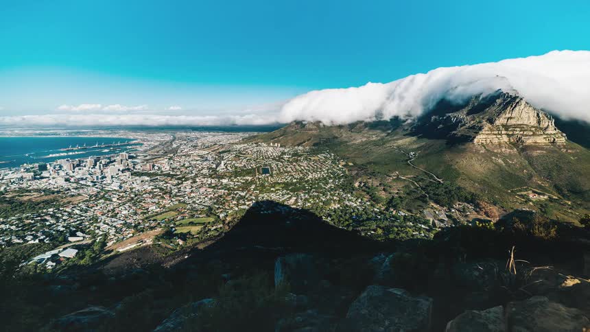 Timelapse of clouds approaching a mountain with a town in front of it