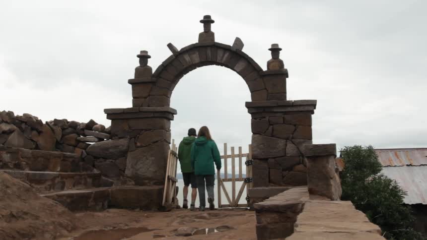 A man and woman holding hands walk towards the water