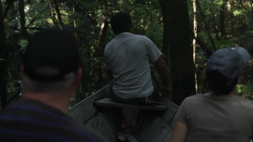 A man paddles a boat through a wooded river