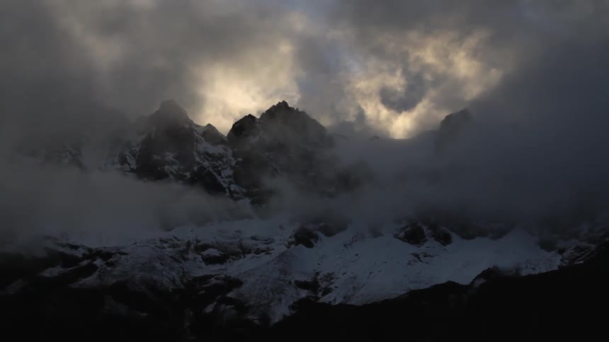 Clouds and fog cover this snow covered mountain