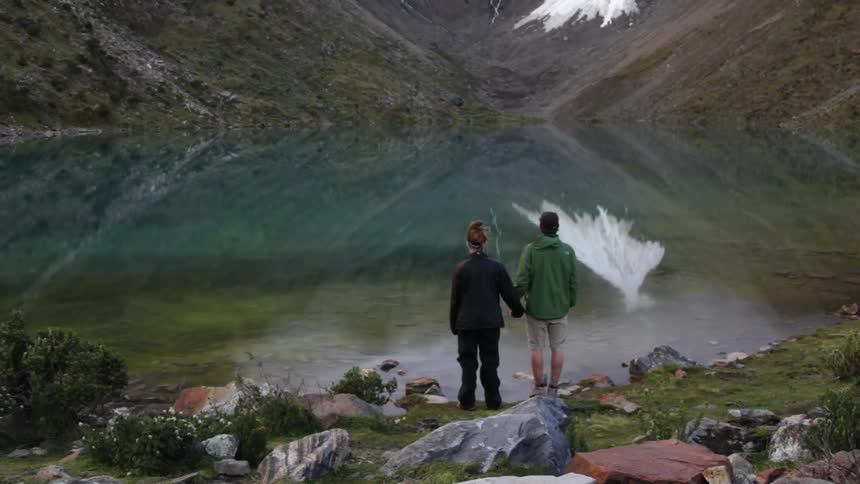 A man and woman are holding hands as they look at a mountain range