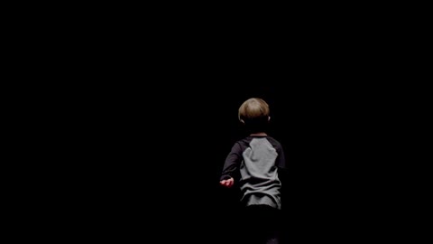 A young boy runs in darkness