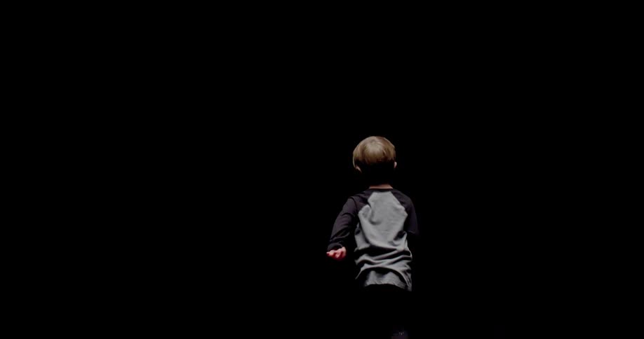 A young boy runs in darkness
