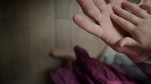 A child puts their hand on their dads hand