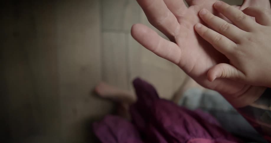 A child puts their hand on their dads hand