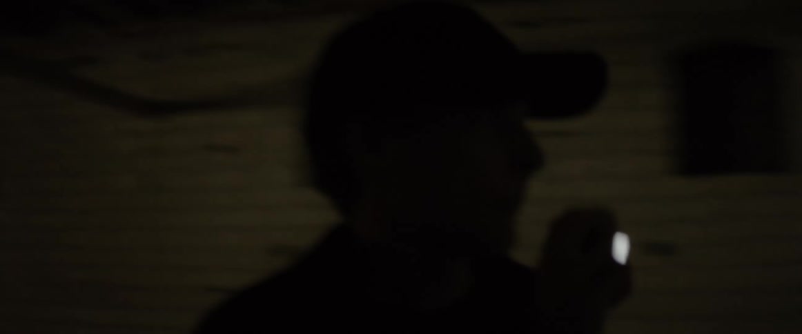 A person shines a flashlight and looks around at night