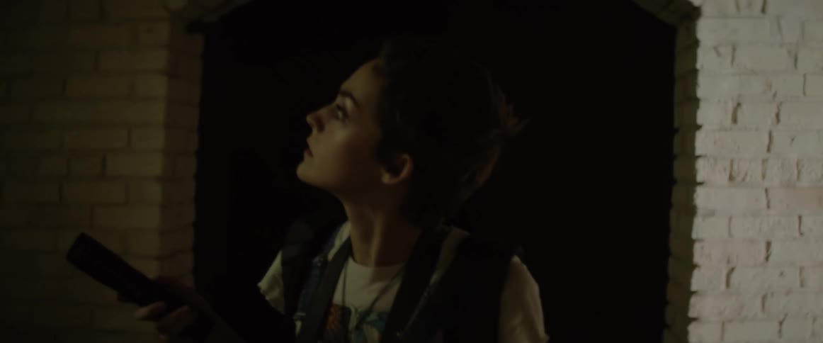 A young woman exploring the dark interior of an old stone structure with a flashlight
