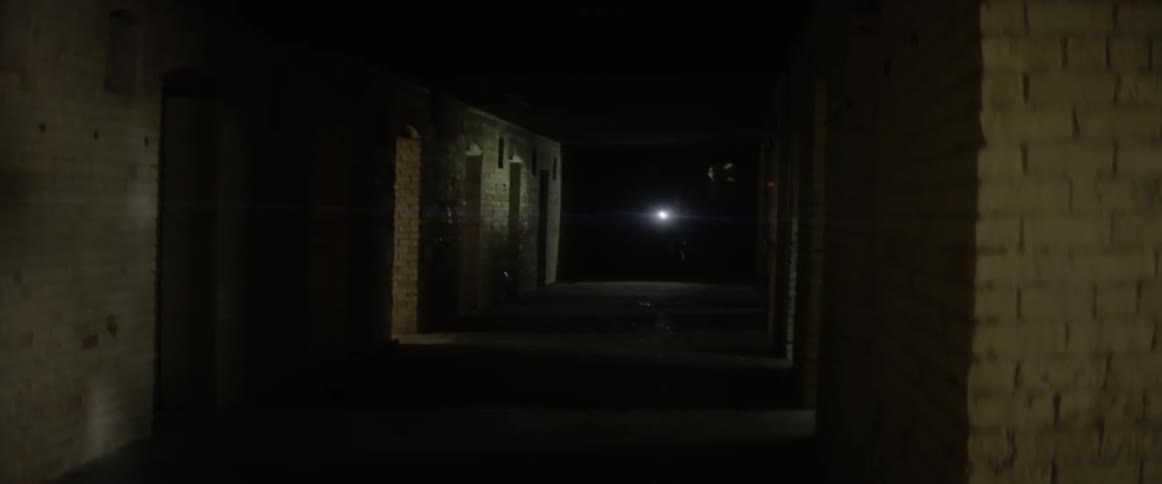 Woman holding a flashlight looks around in a dark corridor