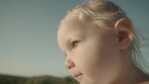 Blonde toddler girl walks along the field