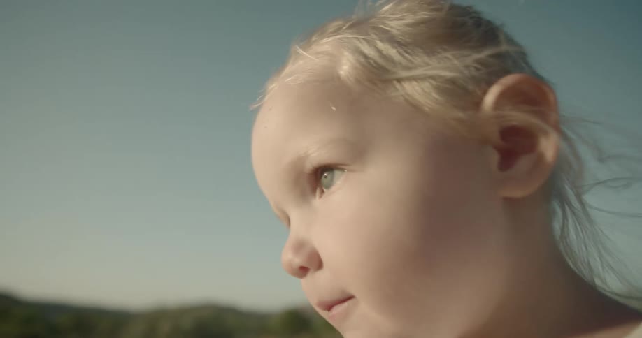 Blonde toddler girl walks along the field