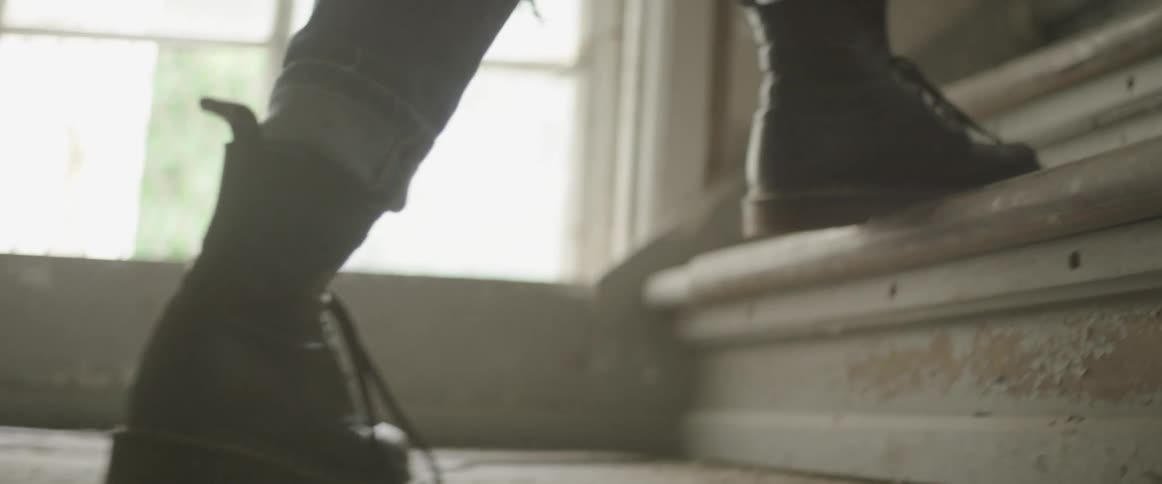 A person wearing boots climbs a staircase in a building