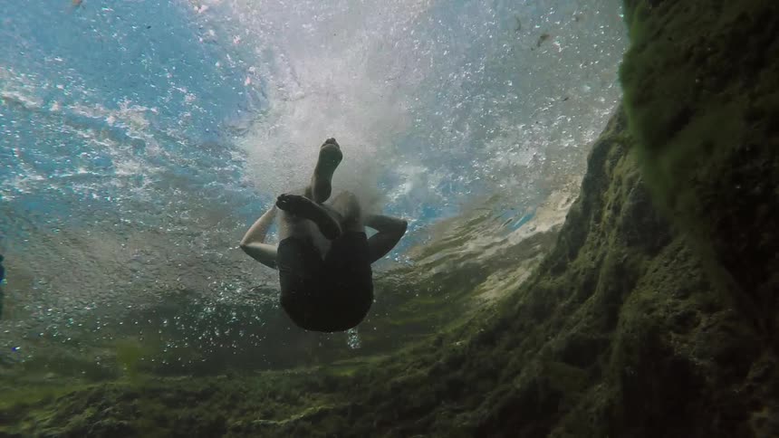 A boy jumps into a swimming hole