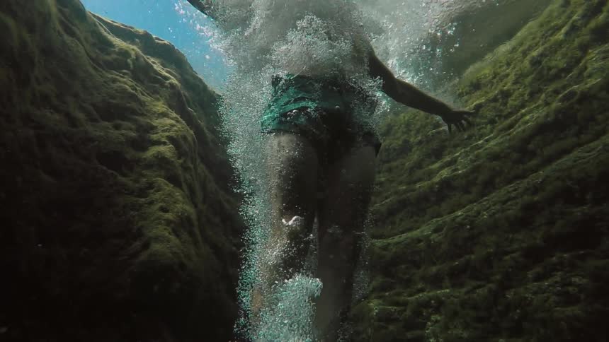 A man jumps from a rock above into water