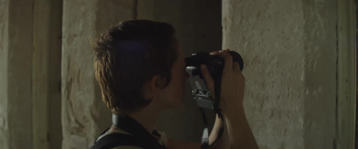 Short haired female photographer takes a picture of the wall in an old building