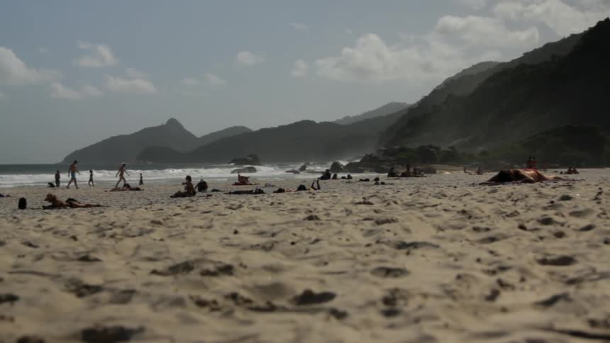 People walking and sitting on the beach on a clear day