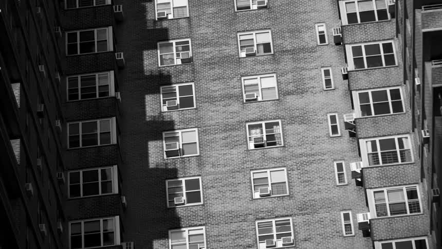A large apartment building looms in a city