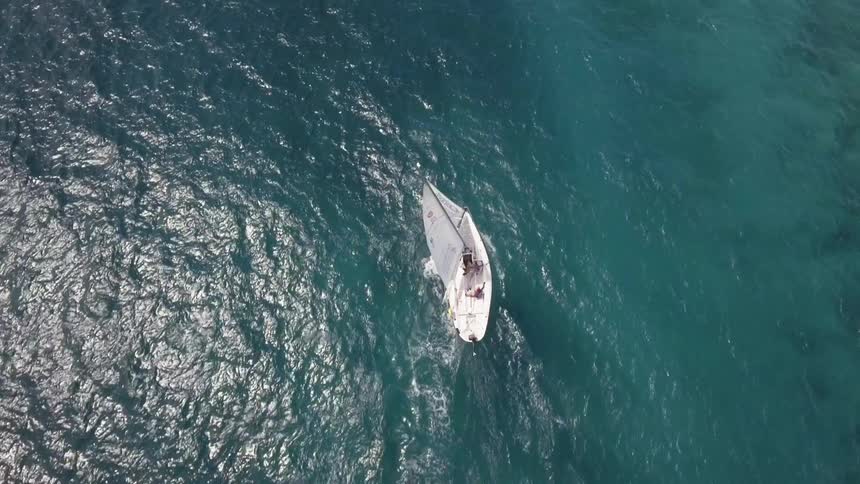 Aerial view of a sailboat traveling on the water on a sunny day