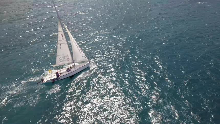 A sailboat with people in the middle of the ocean