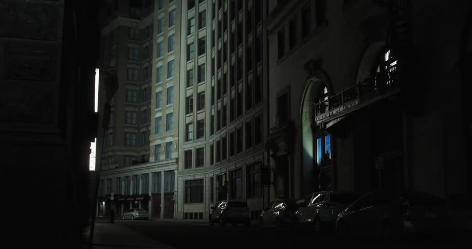 Cars are parked on a city street at night