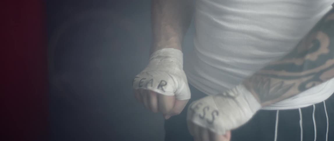 A man with his hands tapedfor a fight hold the up to show the word fearless written across his knuckles