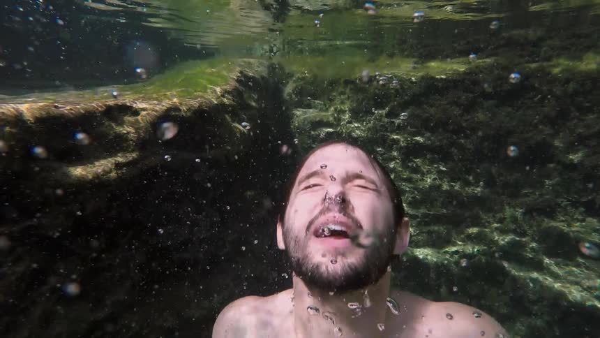 A man swims towards the surface of a lake