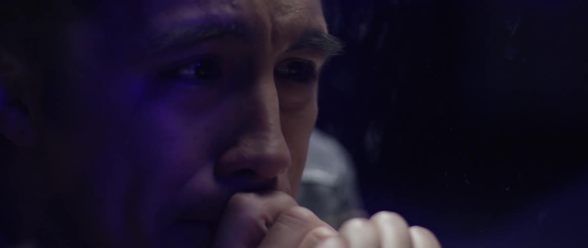 A man crying while sitting in a dimly lit room