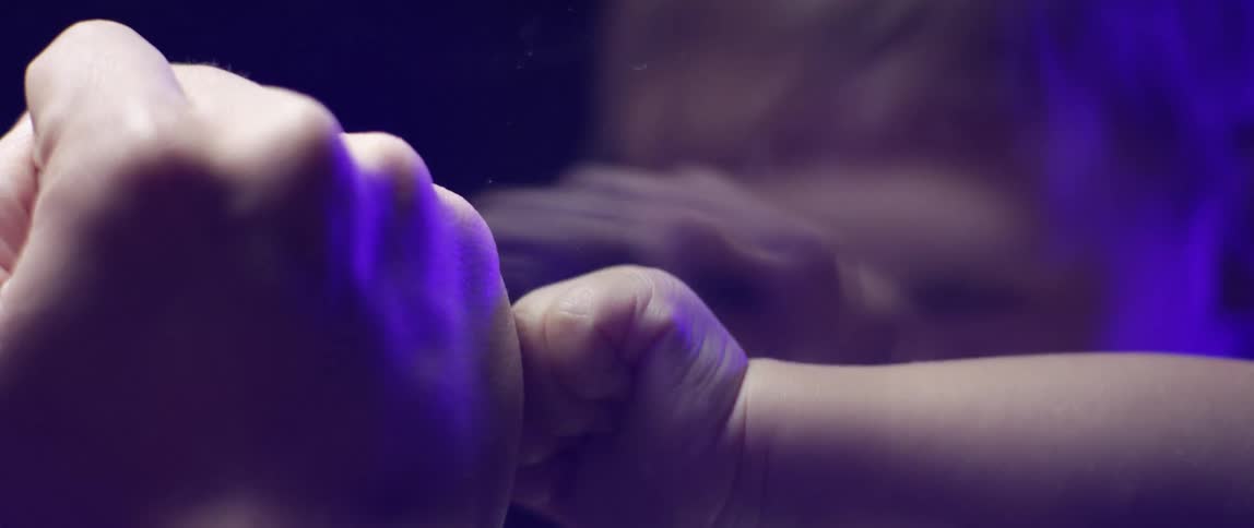 A little girl touches the glass and laughs as she plays with her dad on the other side