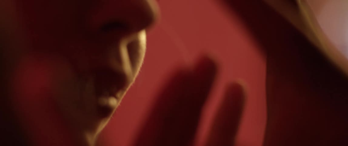 A man and a woman looking at each other through a glass then putting their hands up against the glass