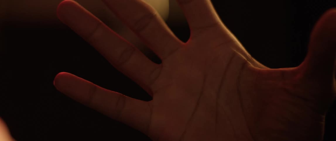 A woman puts her hand up against glass where someone else has their hand
