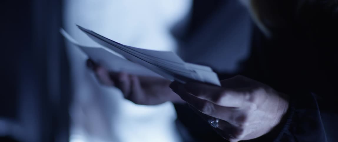 Woman sorts through a handful of pictures in a dim lit room