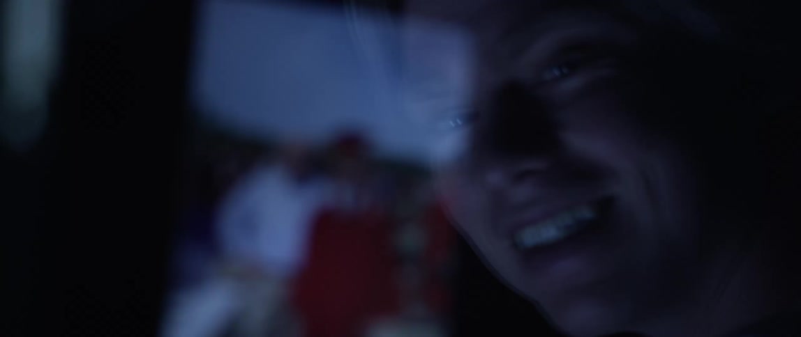 A person smiling and looking at a graduation picture through a glass