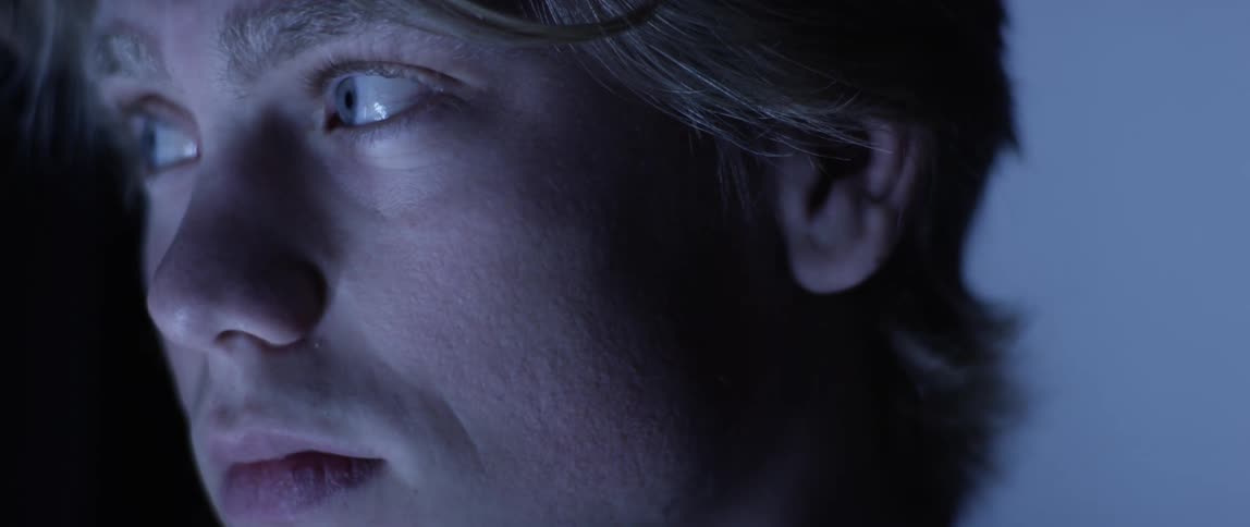 A man is in a dark lit room