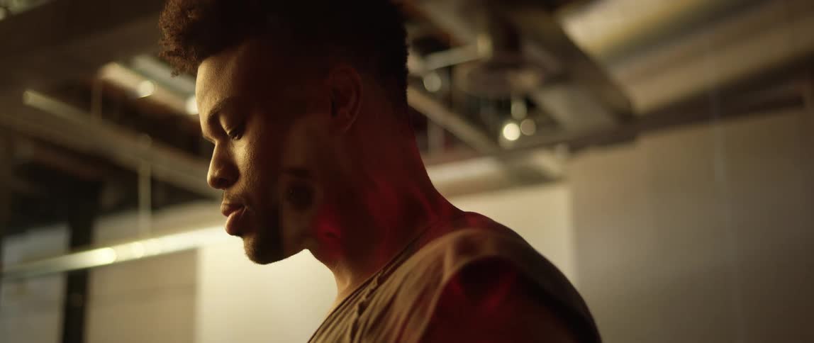 A black man stands inside a building and turns his head to look at something