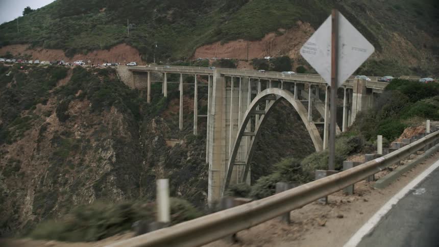Cars travel across large arch bridge over deep gorge