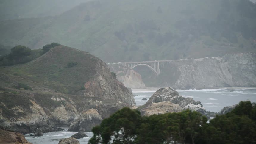 A rocky coastline at the bottom of a mountain during the day