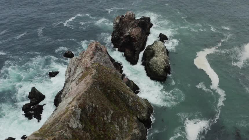 Aerial views of ocean waves crashing against rocks