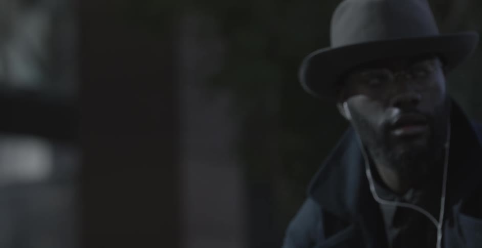 A man in a hat and glasses rides a bike while listening to music using earbuds