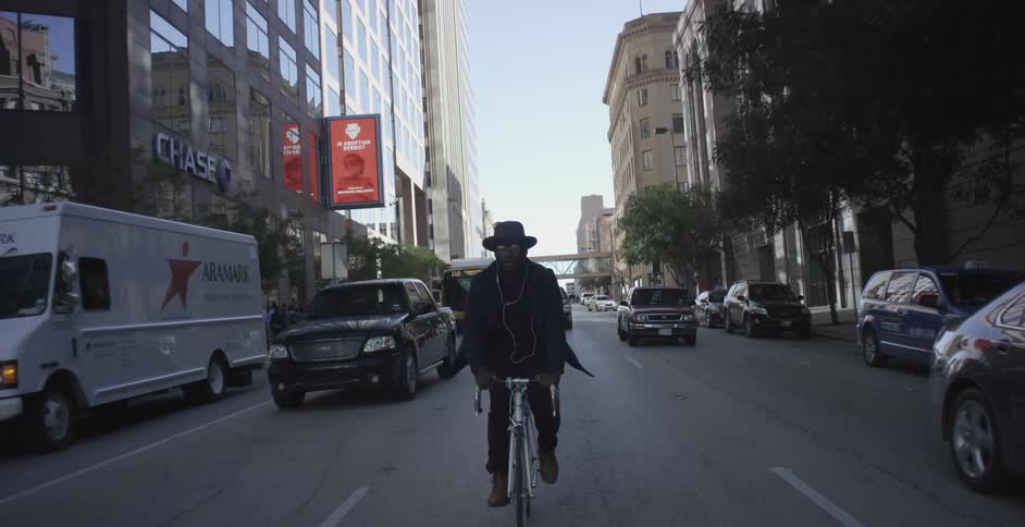 Man rides a bicycle down the middle of a busy city street