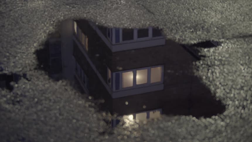 A puddle on the ground reflects a building