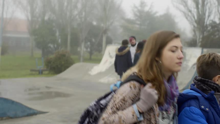 An older sister pulls her brother away from a group of kids