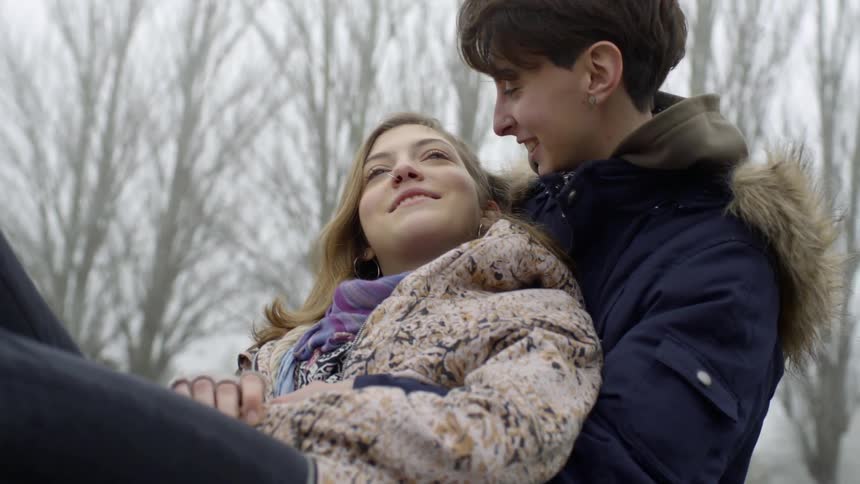 Short haired woman puts her arms around the blonde woman and holds her in a loving way