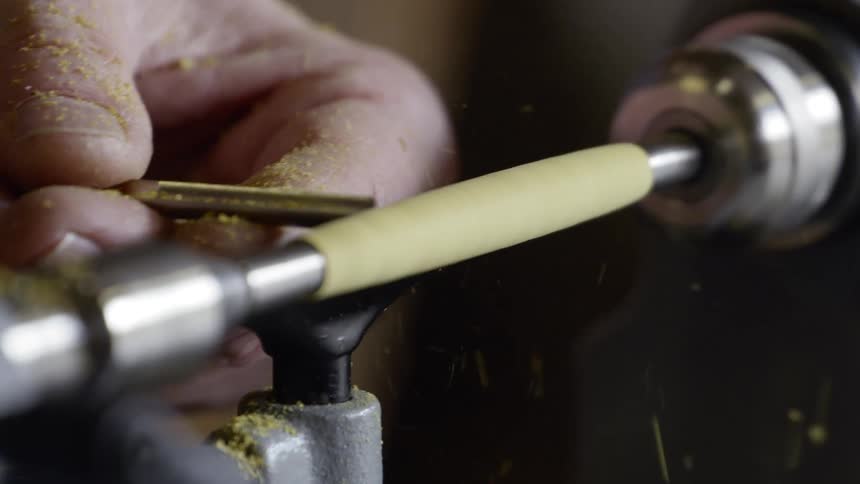Man grinds a piece of metal on a grinder