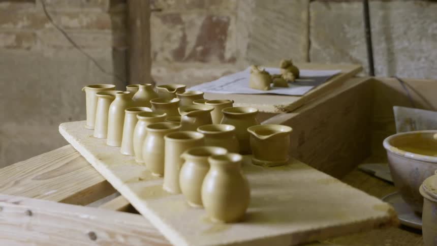 An artist makes small clay cups and vessels