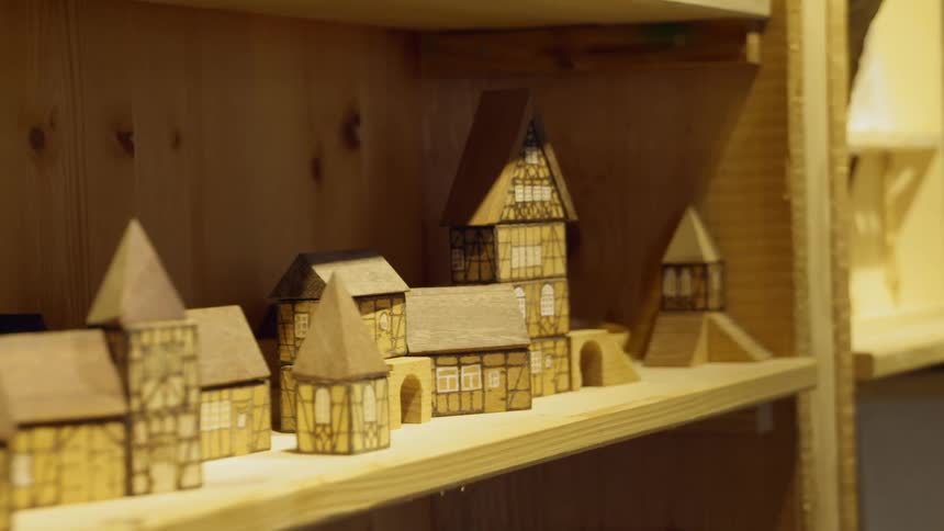 Small wooden houses sit on a wood shelf in a room